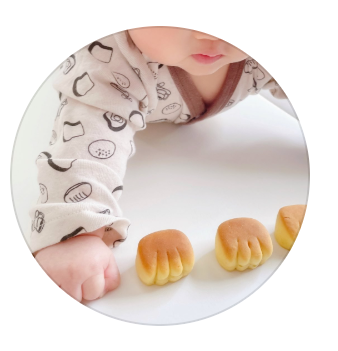 パンライターまなつさんのプロフィール画像。赤ちゃんの手と、その手の形にそっくりなパンが並んでいるかわいい写真。