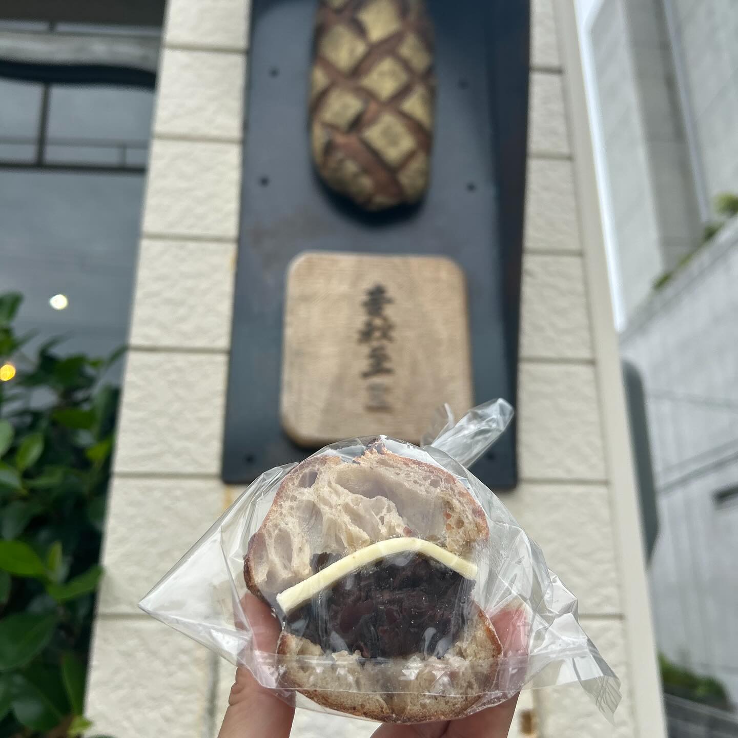 日本の兵庫県神戸市にあるベーカリー、麦秋至さんのお店の前で、あんバターのパンとお店の看板を撮影。
