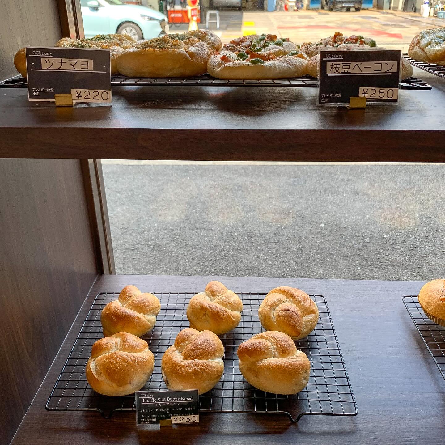 日本の大阪・西天満にあるCC Bakeryの店内写真。
棚の上段にツナマヨと枝豆ベーコンの総菜パンが、下段にトリュフ塩パンが写っている。