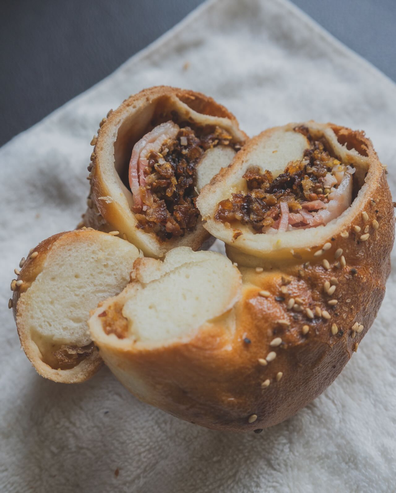 日本の東京都中央区日本橋小伝馬町にあるひふみベーグルさんのベーグル。オニオンベーコンのベーグルサンドの断面写真。
