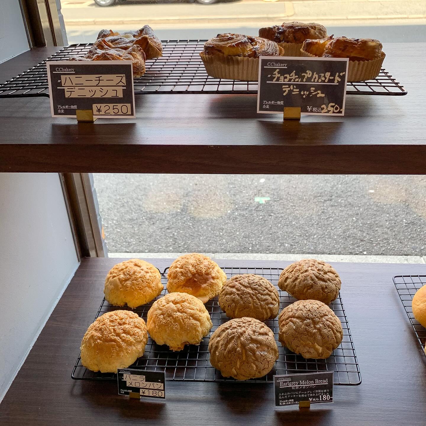 日本の大阪・西天満にあるCC Bakeryの店内写真。
棚の上段にハニーチーズデニッシュとチョコチップカスタードデニッシュが、下段にバニラメロンパンと紅茶メロンパンが写っている。