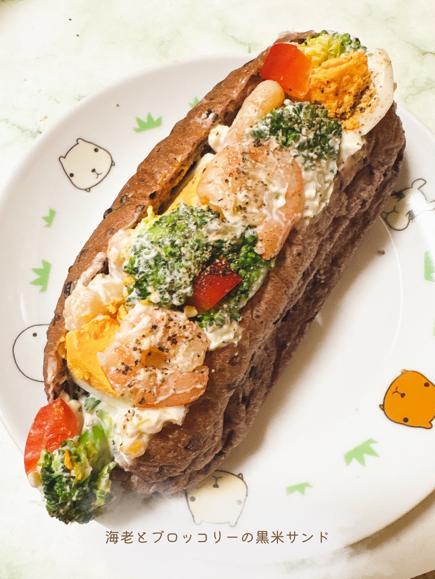 日本の千葉県松戸市にある、石窯パン工房サフラン 新松戸店のパンの写真。海老とブロッコリーの黒米サンド。