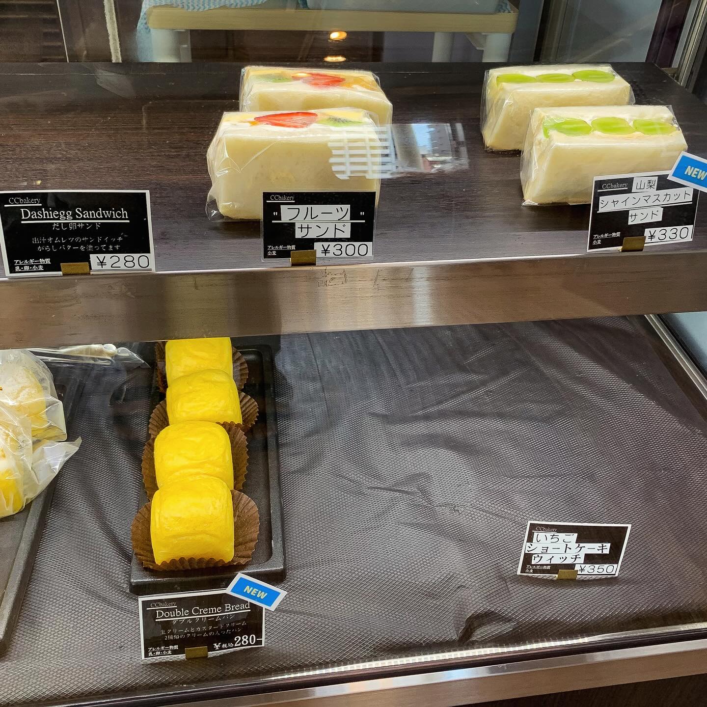 日本の大阪・西天満にあるCC Bakeryの店内写真。
ショーケース内にフルーツサンド、シャインマスカットサンド、ダブルクリームパンが並んでいる。
